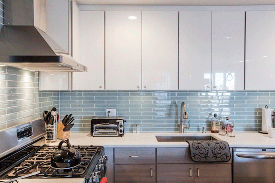Τα πάνω ντουλάπια της κουζίνας είναι λευκή λάκα ενώ τα κάτω laminate σε μια διακριτική ριγέ απόχρωση του ανοιχτού μπεζ – γκρι. 